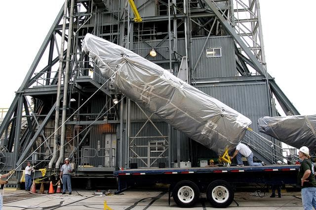 NASA image: KENNEDY SPACE CENTER, FLA. - At Launch Complex 17-A, Cape Canaveral Air Force Station, the first half of the fairing for the Mars Exploration Rover 2 (MER-2/MER-A) is lifted off the transporter.  The fairing will be installed around the payload for protection during launch.  The MER Mission consists of two identical rovers designed to cover roughly 110 yards each Martian day over various terrain. Each rover will carry five scientific instruments that will allow it to search for evidence of liquid water that may have been present in the planet's past.  Identical to each other, the rovers will land at different regions of Mars.  Launch date for MER-A  is scheduled for June 5.
