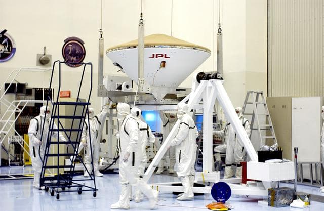 NASA image: KENNEDY SPACE CENTER, FLA. -  An overhead crane is in place to lift the Mars Exploration Rover 2 (MER-2) entry vehicle to move it to a spin table for a dry-spin test.  The MER Mission consists of two identical rovers designed to cover roughly 110 yards each Martian day over various terrain. Each rover will carry five scientific instruments that will allow it to search for evidence of liquid water that may have been present in the planet's past.  Identical to each other, the rovers will land at different regions of Mars.  Launch for MER-2 (MER-A) is scheduled for June 5.