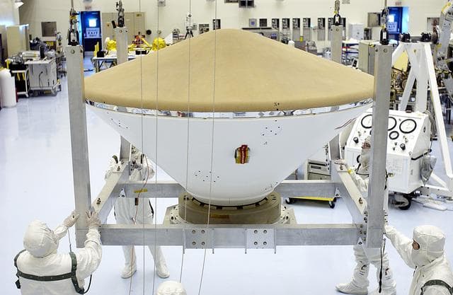 NASA image: KENNEDY SPACE CENTER, FLA. - An overhead crane moves the Mars Exploration Rover 2 (MER-2) entry vehicle across the Payload Hazardous Servicing Facility toward a spin table for a dry-spin test.  The MER Mission consists of two identical rovers designed to cover roughly 110 yards each Martian day over various terrain. Each rover will carry five scientific instruments that will allow it to search for evidence of liquid water that may have been present in the planet's past.  Identical to each other, the rovers will land at different regions of Mars.  Launch for MER-2 (MER-A) is scheduled for June 5.