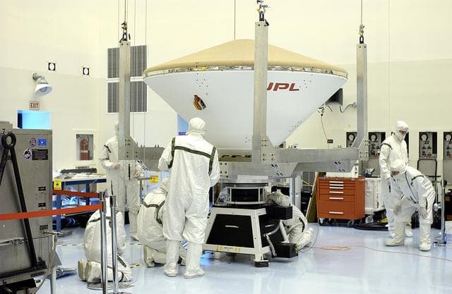 NASA image: KENNEDY SPACE CENTER, FLA. - The overhead crane settles the Mars Exploration Rover 2 (MER-2) entry vehicle onto a spin table for a dry-spin test.  The MER Mission consists of two identical rovers designed to cover roughly 110 yards each Martian day over various terrain. Each rover will carry five scientific instruments that will allow it to search for evidence of liquid water that may have been present in the planet's past.  Identical to each other, the rovers will land at different regions of Mars.  Launch for MER-2 (MER-A) is scheduled for June 5.