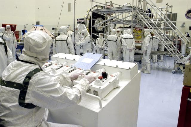 NASA image: KENNEDY SPACE CENTER, FLA. - Workers in the Payload Hazardous Servicing Facility are preparing to determine weight and center of gravity for the Mars Exploration Rover 2 (MER-2).  NASA's twin Mars Exploration Rovers are designed to study the history of water on Mars. These robotic geologists are equipped with a robotic arm, a drilling tool, three spectrometers, and four pairs of cameras that allow them to have a human-like, 3D view of the terrain. Each rover could travel as far as 100 meters in one day to act as Mars scientists' eyes and hands, exploring an environment where humans can't yet go.  Launch of MER-2 is scheduled for June 5 from Cape Canaveral Air Force Station.